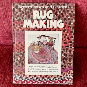May include: A hardcover book titled Better Homes and Gardens RUG MAKING. The cover features a multi-colored braided pattern and a central inset image showing a dark wooden bench, a braided oval rug, and potted flowers. Text includes project details.