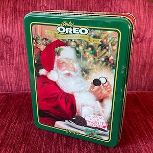 May include: Green rectangular Oreo cookie tin featuring Santa Claus holding an Oreo cookie. The tin reads "Only Oreo 85th Anniversary Edition 1912-1997" and "For Santa, Your Favorite Cookies."