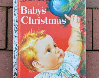 May include: A vintage "Baby's Christmas" Little Golden Book. The cover features a baby reaching for a blue Christmas ornament. The book has a red background with the title in white letters. The baby has blonde hair and is wearing a white and blue outfit.