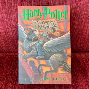 May include: A paperback copy of the book "Harry Potter and the Prisoner of Azkaban" by J.K. Rowling. The cover features a colorful illustration of Harry Potter riding a Hippogriff.