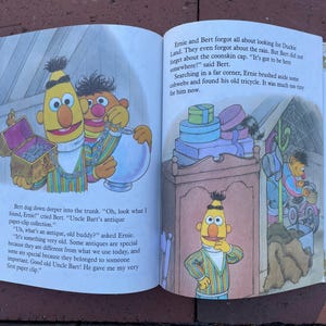 May include: A children's book illustration featuring Sesame Street characters Bert and Ernie. Bert and Ernie are shown in a colorful scene with text from the story. The book is open, displaying the artwork and text.