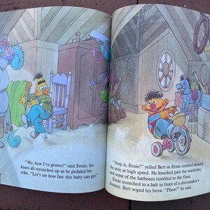 May include: A colorful illustration from a children's book featuring Sesame Street characters Ernie and Bert. Ernie is shown on a tricycle, and the text reads, "My, how I've grown!" and "Stop it, Ernie!"