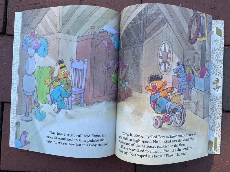 May include: A colorful illustration from a children's book featuring Sesame Street characters Ernie and Bert. Ernie is shown on a tricycle, and the text reads, "My, how I've grown!" and "Stop it, Ernie!"