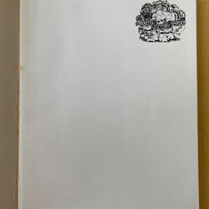 May include: A white page from a book featuring a black and white ink illustration of a head of lettuce in the upper right corner. A banner draped across the lettuce contains the text Crockett's Victory Garden in a clear, legible font.