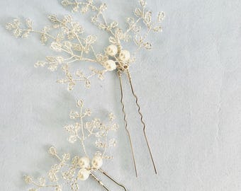 Puede incluir: Tres horquillas de pelo plateadas con delicadas ramas de cuentas y detalles de perlas. Las ramas están hechas de alambre plateado y están adornadas con pequeñas cuentas transparentes. Las perlas son blancas y están agrupadas al final de cada rama.