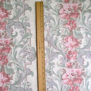 May include: Vintage wallpaper with a repeating floral pattern. The design features large pink roses, gray and green foliage, and a white background. A wooden ruler, approximately 30 cm long, is placed vertically on the wallpaper.