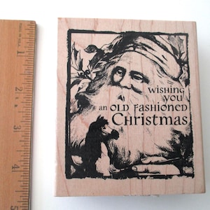 May include: Wooden stamp with a black and white illustration of Santa Claus and a horse, with the text "wishing you an OLD FASHIONED Christmas." A wooden ruler is next to the stamp.