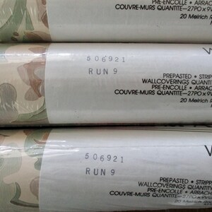 May include: Three rolls of pre-pasted, strippable wallpaper. The wallpaper features a repeating pattern of green, brown, and beige organic shapes. The label reads "WALLCOVERINGS QUANTITY - 27 IN. x 9". The text "506921 RUN 9" is also visible.