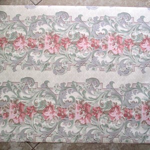 May include: Wallpaper with a repeating floral pattern. The design features rows of pink roses and grey, green, and white scrollwork on a cream background. The wallpaper has a vintage aesthetic.