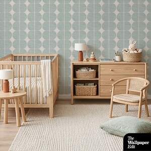 Op de afbeelding: Een kinderkamer met licht houten meubels, waaronder een wieg, een dressoir en een bijzettafel. De muren zijn versierd met een blauw en wit behang met patroon. Een geweven vloerkleed en stoel voegen textuur toe. Decoratieve items zijn lampen, manden en een knuffelkonijn.
