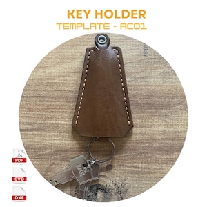 May include: Brown leather key holder with a stitched edge and a silver metal ring. The key holder is on a wooden surface. The image includes the text "KEY HOLDER TEMPLATE - AC01".