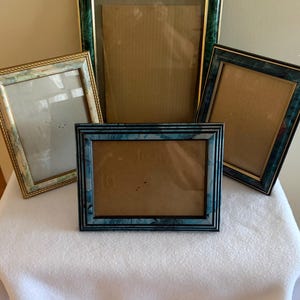 May include: A collection of four rectangular picture frames. One large frame features a green marbled pattern with gold trim. Two smaller frames have blue marbled designs with black or gold accents. One frame has a light blue and white pattern.
