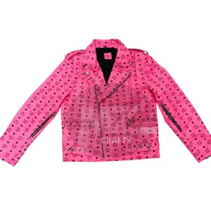 Könnte beinhalten: Eine leuchtend pinkfarbene Motorradjacke mit schwarzem Innenfutter und schwarzen Reißverschlüssen. Die Jacke hat ein sich wiederholendes Muster aus schwarzen Logos. Das Wort "CRAFTS" ist auf die Jacke gedruckt.