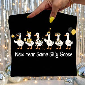 May include: Black pillowcase featuring a line of cartoon geese dressed for a New Year's celebration. The geese are wearing sunglasses, party hats, and holding champagne glasses and balloons. The text "New Year Same Silly Goose" is printed below the geese.