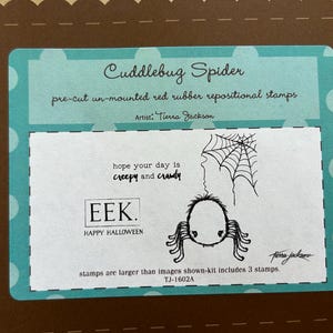 May include: A teal card with the words "Cuddlebug Spider" and "Happy Halloween" printed on it. The card features a spider illustration, a spider web, and the text "hope your day is creepy and crawly".