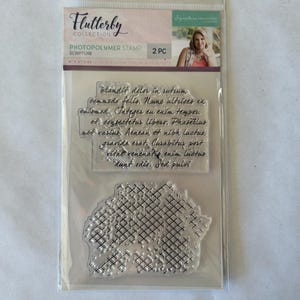 May include: A clear photopolymer stamp set with two stamps. The first stamp features a scripture quote in black ink. The second stamp features a decorative pattern of intersecting lines.