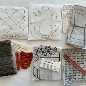 May include: A collection of craft supplies, including rubber stamps and paper templates for creating decorative boxes and baskets. The stamps feature basket weave and gift box designs. The templates include dotted lines for folding.