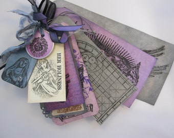 May include: A collection of purple and gray paper tags with a black ribbon and a round, pink, floral design. The tags have various images and text, including "HER HOLINESS".