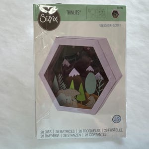 May include: A Sizzix Thinlits die set featuring a hexagonal shadow box design with a forest scene. The scene includes trees, mountains, and animal cutouts. The packaging includes the text "JESSICA SCOTT" and "28 DIES".