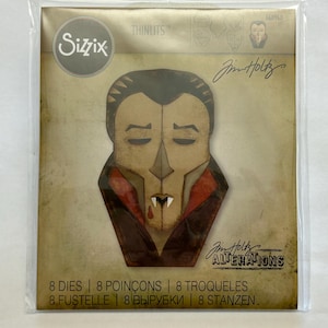 May include: A Sizzix Thinlits die set package featuring a graphic illustration of a vampire face with a high collar, dark hair, and fangs. The packaging includes the text Sizzix, Tim Holtz, Alterations, and indicates a set of 8 dies included.