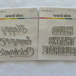 May include: Two packages of word dies for scrapbooking. One package includes the words "Happy", "Birthday", and "Graduation". The other package includes "Hello", "Thanks", and "Celebrate". Each package has 3 pieces.
