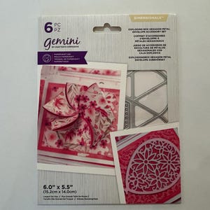 May include: A craft kit for making an exploding box with hexagon petal envelope accessories. The package includes a die set and sample images of the finished product. The dimensions are 6.0" x 5.5" (15.2cm x 14.0cm).
