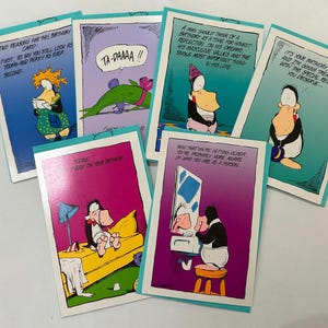 May include: A collection of six birthday greeting cards with cartoon illustrations and humorous text. Each card features a different design with a teal border and a white background. The cards have various characters and speech bubbles.
