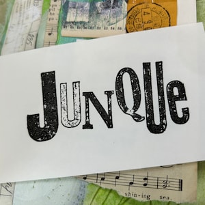 May include: A white card with the word "Junolle" printed in black, block letters with a distressed, vintage look.