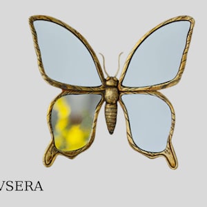 May include: A butterfly-shaped wall mirror with a gold-colored metal frame. The mirror has two large wings and a body, with a reflective surface. The text "EVSERA" is at the bottom.