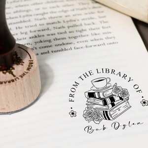 May include: A black and white illustration of a stack of books with a cup of coffee on top. The illustration is surrounded by a circle with the text "From the Library of" and the name "Bob Dylan".