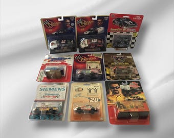 May include: A collection of die-cast race cars in their original packaging. The cars feature various designs and sponsor logos, with some including the driver's image. The packaging is in various colors, including red, black, and blue.