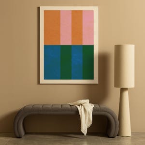 May include: A framed abstract art print with vertical stripes in orange, pink, blue, and green hues. The artwork hangs above a gray upholstered bench with a cream-colored throw. A beige floor lamp stands to the right.