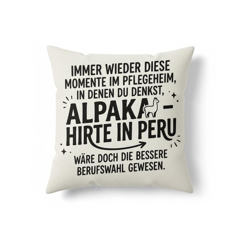 May include: A square, off-white pillow with black text. The text reads "IMMER WIEDER DIESE MOMENTE IM PFLEGEHEIM, IN DENEN DU DENKST, ALPAKA - HIRTE IN PERU W&Auml;RE DOCH DIE BESSERE BERUFSWAHL GEWESEN."