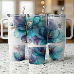 Könnte beinhalten: Drei Edelstahlbecher mit Deckel und Strohhalmen. Jeder Becher zeigt ein anderes Blumenmuster mit blauen, violetten und goldenen Akzenten auf weißem Hintergrund.
