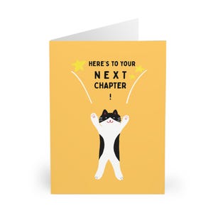Könnte beinhalten: Eine Grußkarte mit gelbem Hintergrund und einer Illustration einer schwarz-weißen Katze. Der Text "HERE'S TO YOUR NEXT CHAPTER!" steht über der Katze. Die Katze ist mit erhobenen Armen dargestellt.