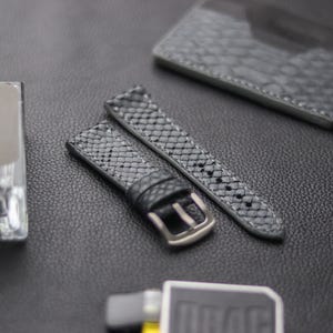 May include: Two gray leather watch straps with a textured pattern. One strap has a silver buckle.