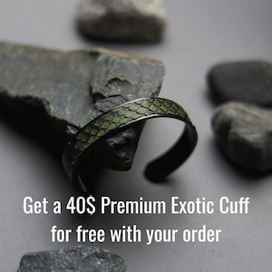 K&ouml;nnte beinhalten: Ein Armreif aus dunklem Metall mit einer strukturierten, olivgr&uuml;nen Einlage in Schuppenoptik. Der Text "Get a 40$ Premium Exotic Cuff for free with your order" ist in Wei&szlig; am unteren Bildrand aufgedruckt.