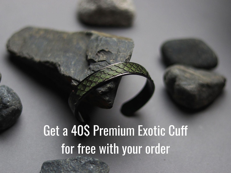 K&ouml;nnte beinhalten: Ein Armreif aus dunklem Metall mit einer strukturierten, olivgr&uuml;nen Einlage in Schuppenoptik. Der Text "Get a 40$ Premium Exotic Cuff for free with your order" ist in Wei&szlig; am unteren Bildrand aufgedruckt.