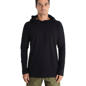 以下が含まれることがあります： 黒色の長袖フード付きシャツ。シンプルなデザインで、フードと長袖が付いています。モデルはオリーブグリーンのパンツを着用しています。シャツは柔らかく快適な素材で作られています。