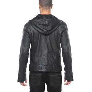 May include: A black leather jacket with a hood. The jacket has a zipper closure and two pockets on the front. The jacket is worn by a person standing with their back to the camera.