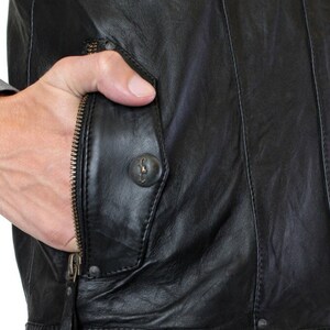 May include: Black leather jacket with a zippered pocket and a button closure. The pocket has a flap with a decorative button.