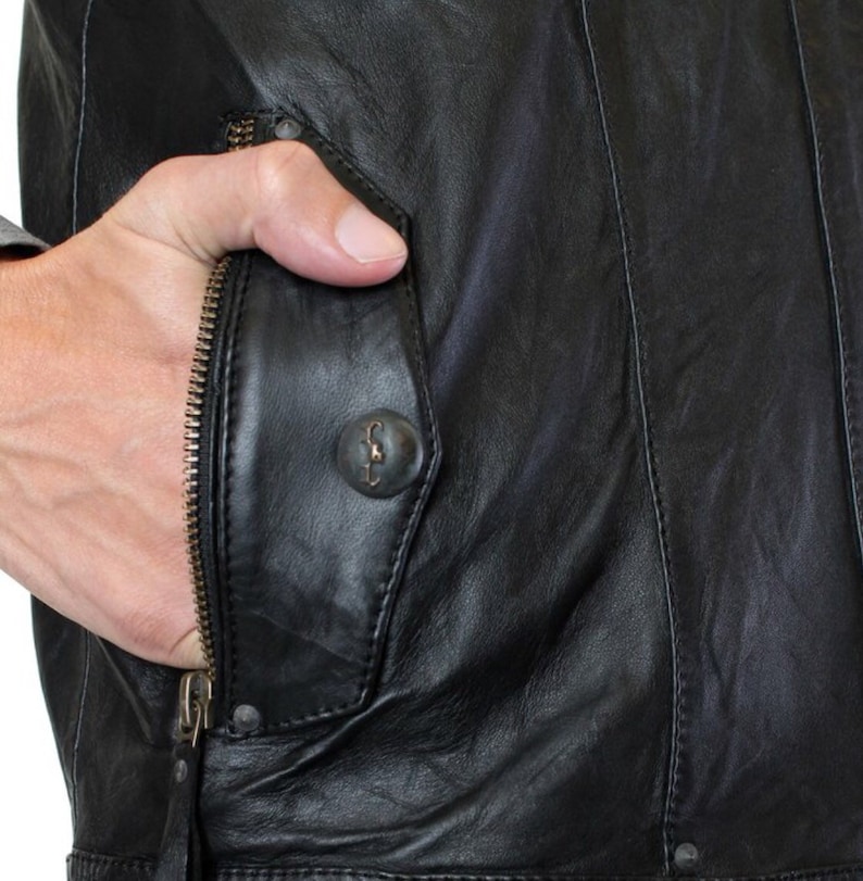 May include: Black leather jacket with a zippered pocket and a button closure. The pocket has a flap with a decorative button.