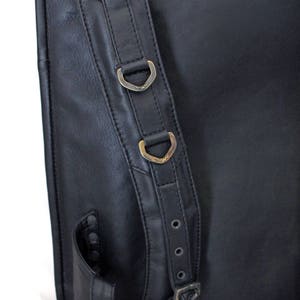May include: Black leather backpack with adjustable straps and metal buckles. The straps have two metal rings for attaching additional items.