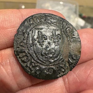 Puede incluir: Una moneda de plata con un escudo y un diseño de flor de lis. La moneda tiene un borde elevado y una superficie lisa. La moneda está en buen estado.