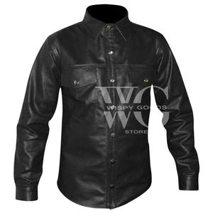Front view of a long-sleeved, collared men's shirt made from textured black leather. The shirt features a central vertical button placket with silver snap fasteners, two symmetrical chest pockets with pointed flaps secured by silver snaps, and a curved hemline. The material has a distinct, fine pebble-grained leather texture.