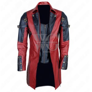 A full-length, front-facing photo of a bold, two-tone real leather trench coat/long jacket in deep red and black. The coat has a dramatic, duster-length cut and features a notched lapel collar. It contrasts red leather on the main body panels with black leather on the shoulders, inner lapels, and portions of the sleeves. The coat is highly detailed with multiple metallic accents, including functional and decorative buckles and straps on the shoulders and cuffs, gothic or rocker aesthetic.