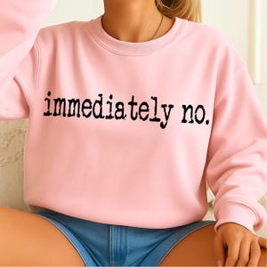 May include: A light pink sweatshirt with the phrase "immediately no." printed in black, bold letters. The sweatshirt has a crew neck and long sleeves. The garment is made of a soft material.