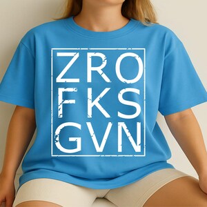 May include: A light blue t-shirt with a white graphic print of the letters "ZRO FKS GVN" in a box.