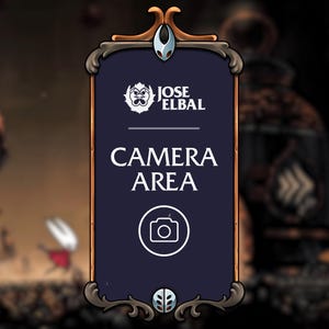 Puede incluir: Un letrero rectangular azul oscuro con adornos marrones y plateados. El letrero presenta el texto "CAMERA AREA" en blanco, junto con un icono de cámara. La parte superior del letrero tiene un elemento decorativo plateado y el logotipo "JOSE ELBAL".