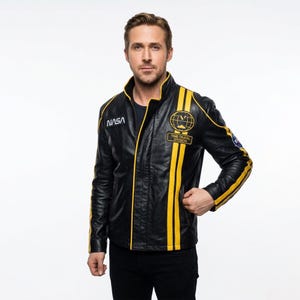 May include: Black leather jacket with yellow stripes and NASA and Time Travel Division patches. The jacket has a stand-up collar and a zip-up front. The jacket is worn by a person.